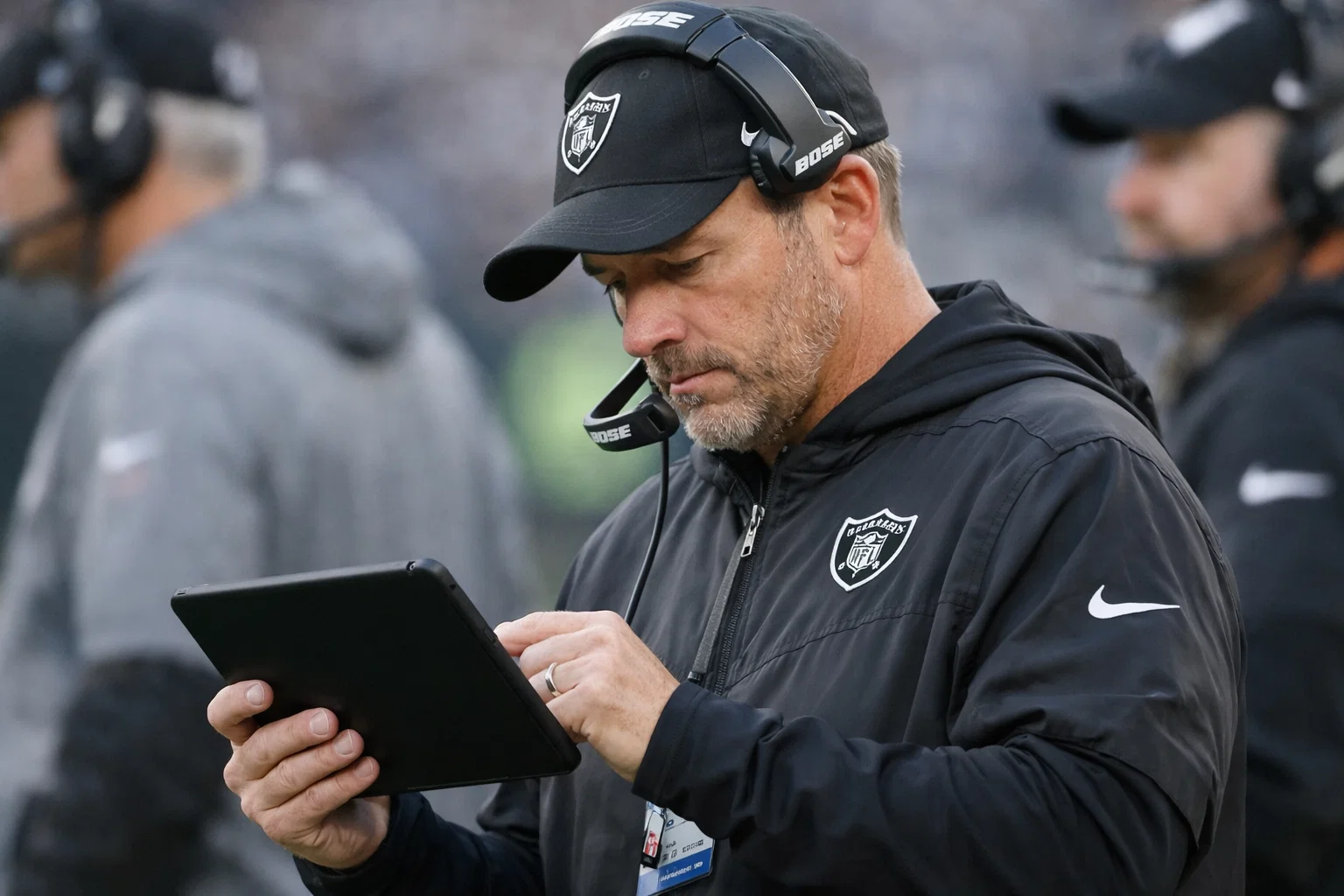 NFL Trainer studiert Spielzüge auf einem Tablet am Spielfeldrand